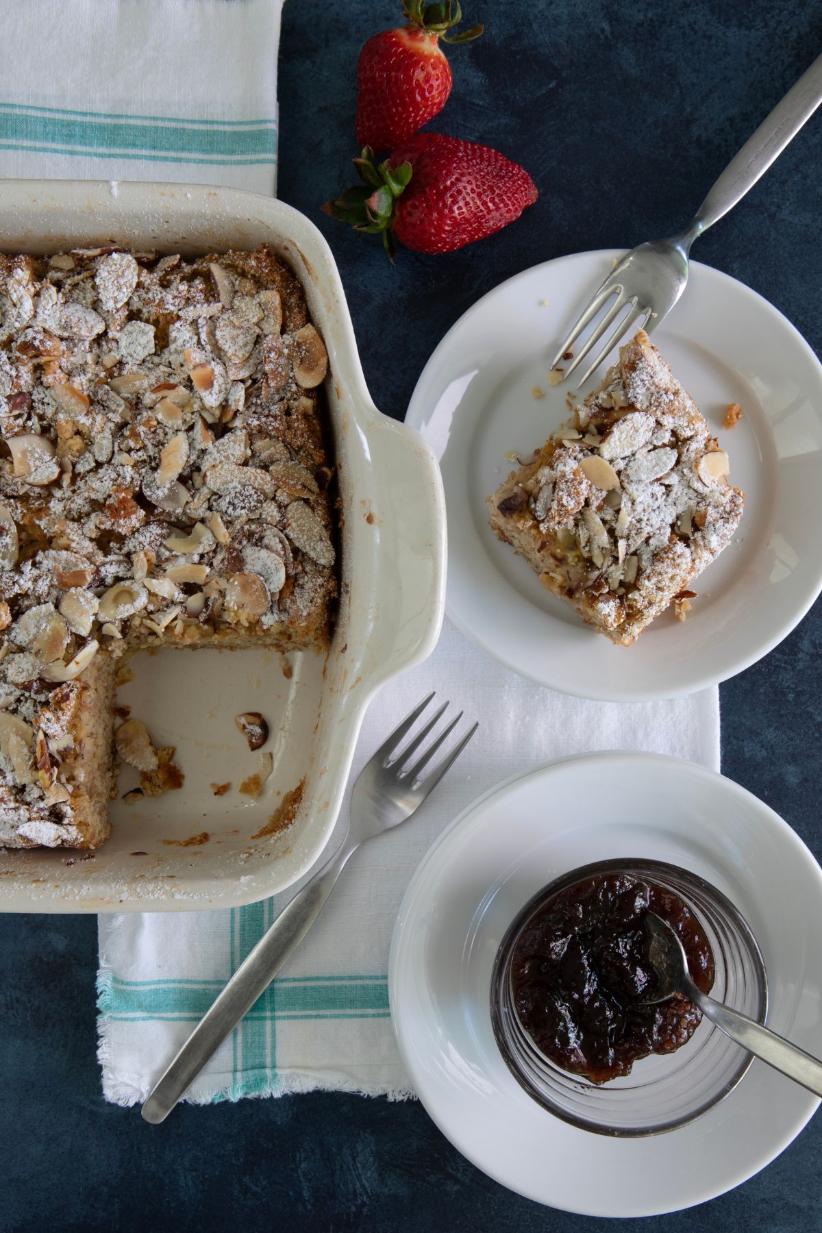a french toast casserole in a baking dish next to a plate with a slice on it