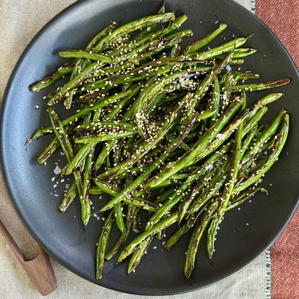 a black plate filled with blistered green beans ready to serve
