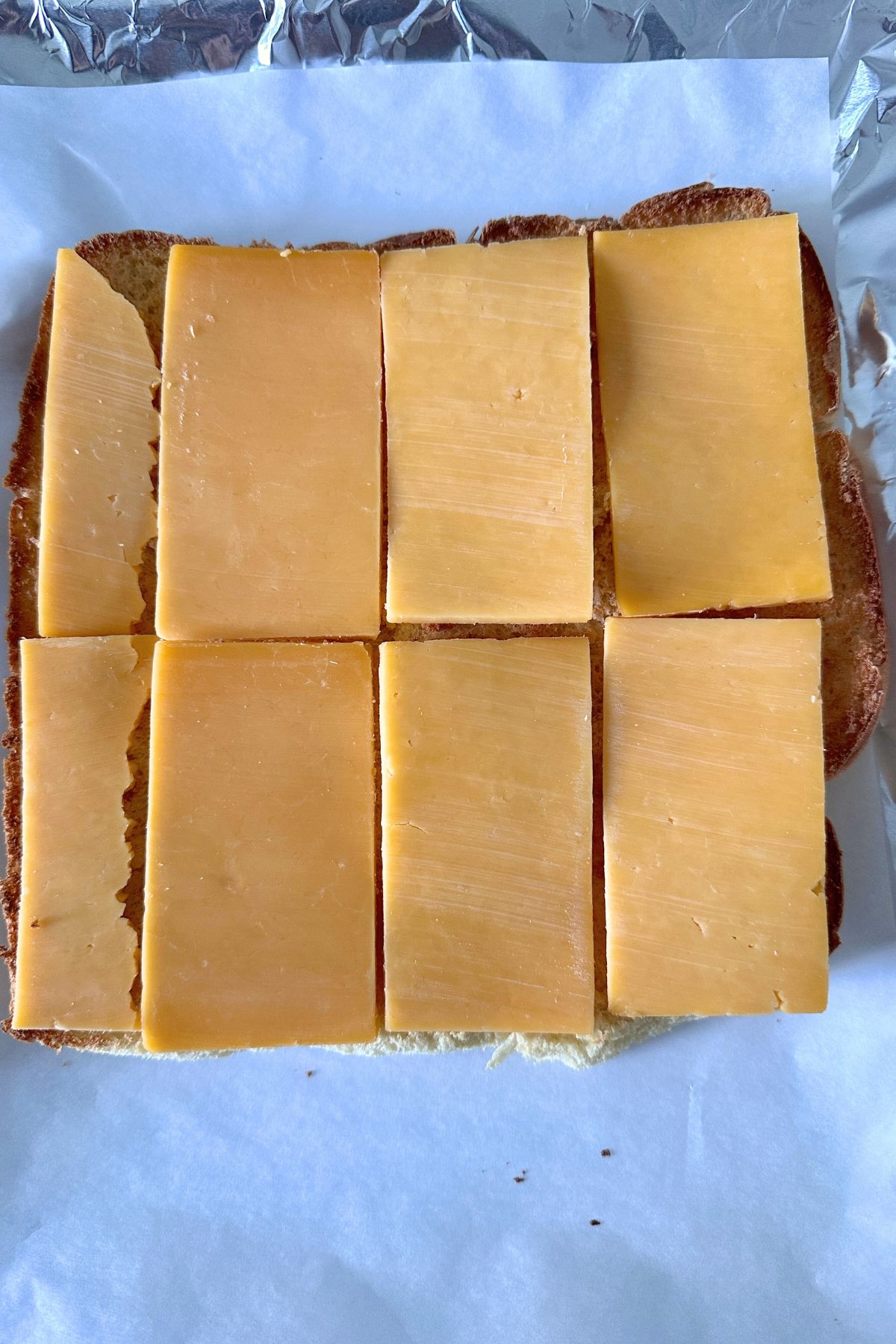 Cheese slices placed over toasted slider bun bottoms.