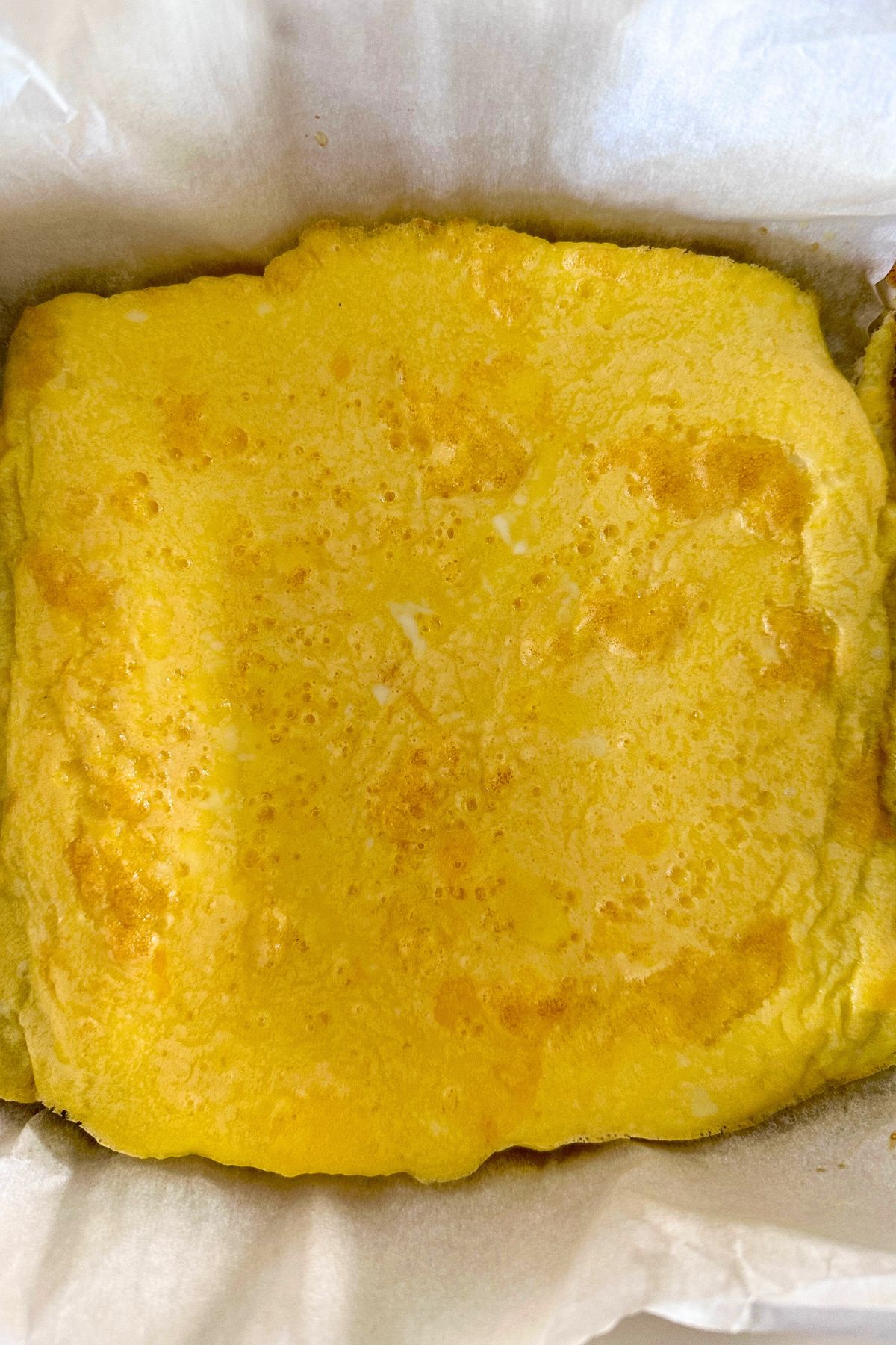 Baked egg layer in a square, parchment-lined pan.