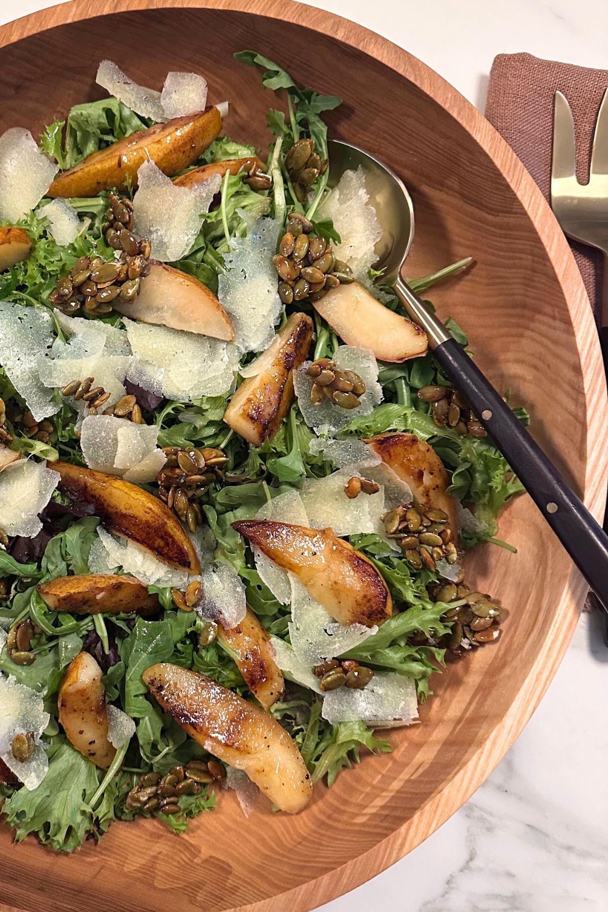 Close-up of caramelized pear salad with crisp greens, blue cheese, and crunchy candied seeds.