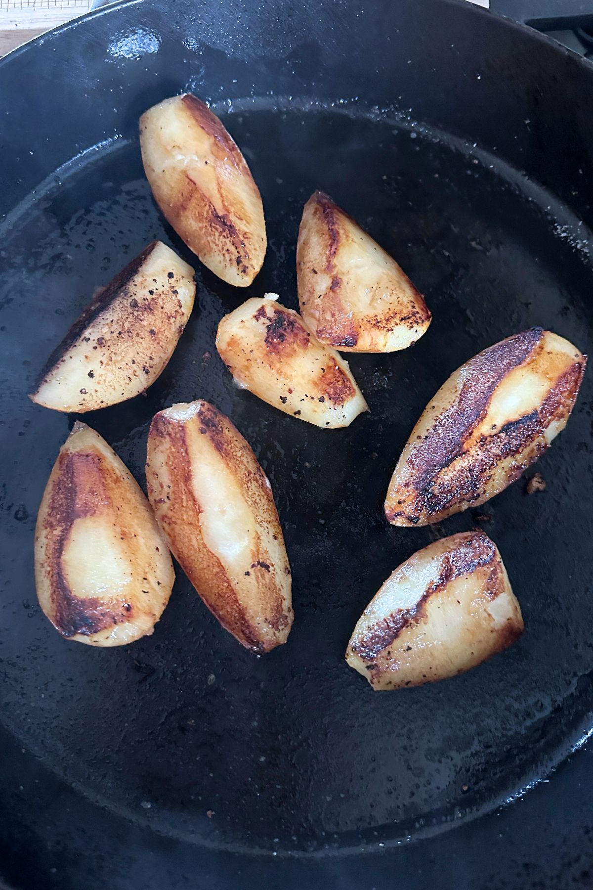 Quartered pears searing in a hot skillet until golden.