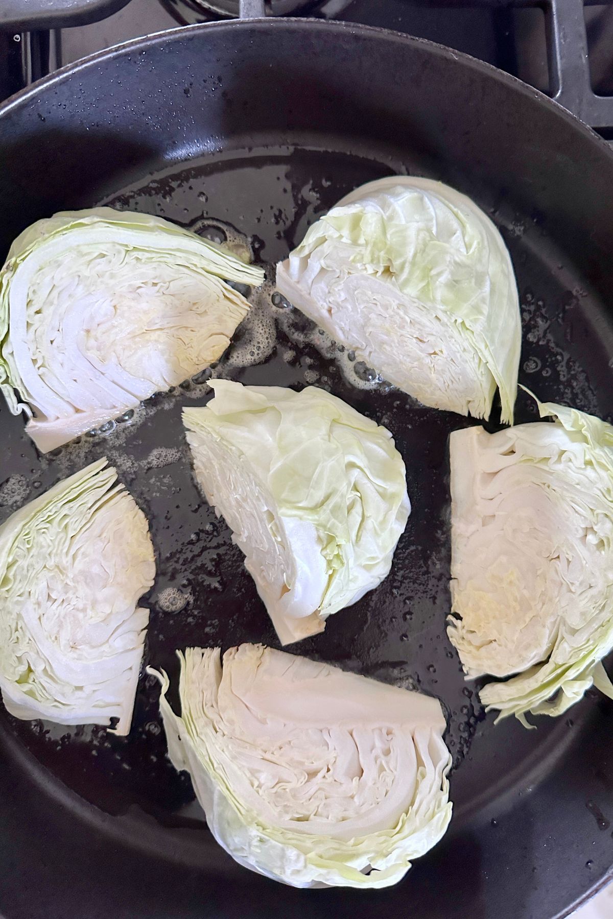Olive oil and butter in a large ovenproof skillet with cabbage wedges cut side down.