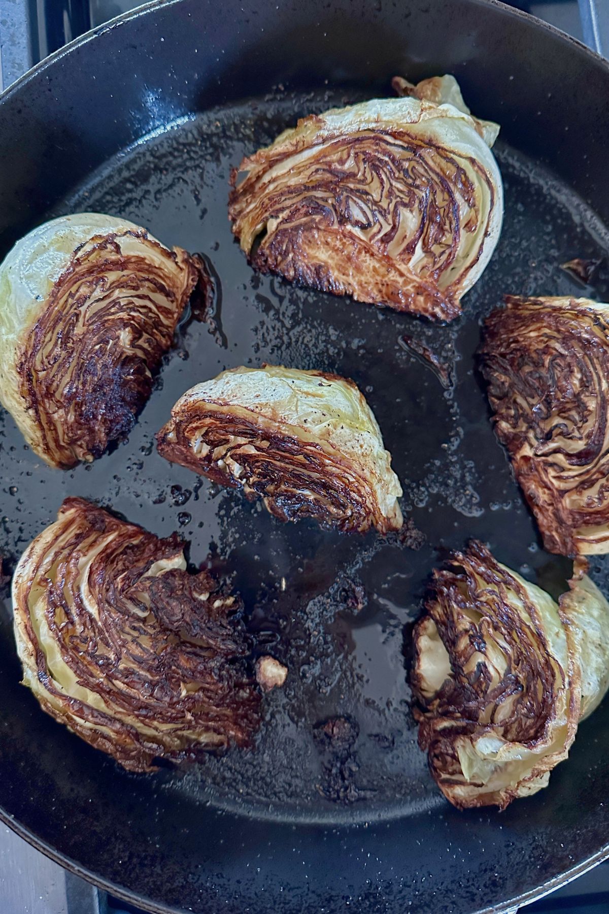 Olive oil and butter in a large ovenproof skillet with browned cabbage wedges.