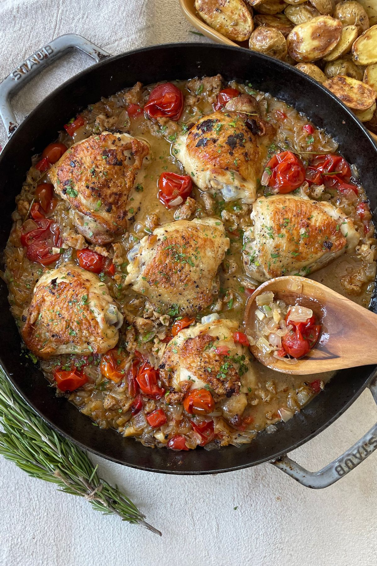 Finished chicken scarpariello served in a skillet, garnished with fresh parsley, with visible chicken thighs, sausage, and peppers in the tangy sauce.