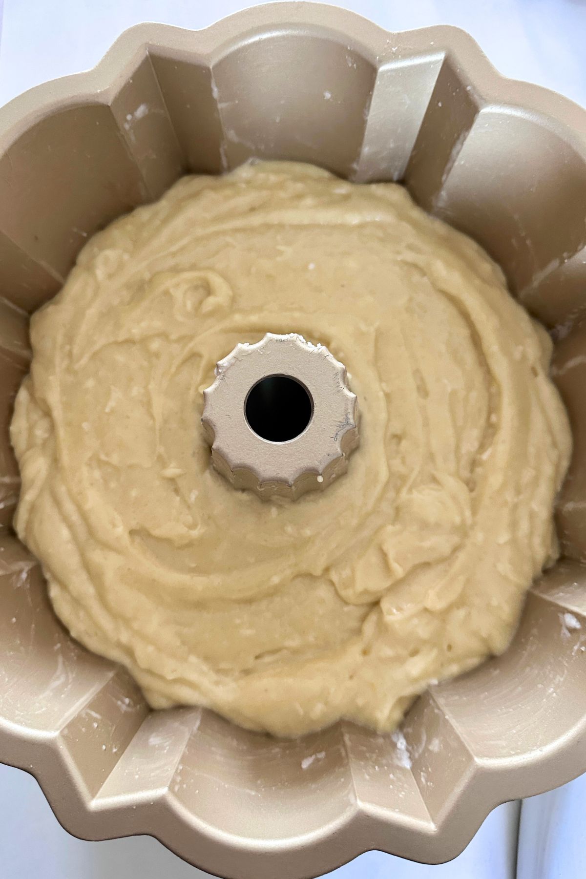 Coconut bundt cake batter poured into a bundt cake pan.