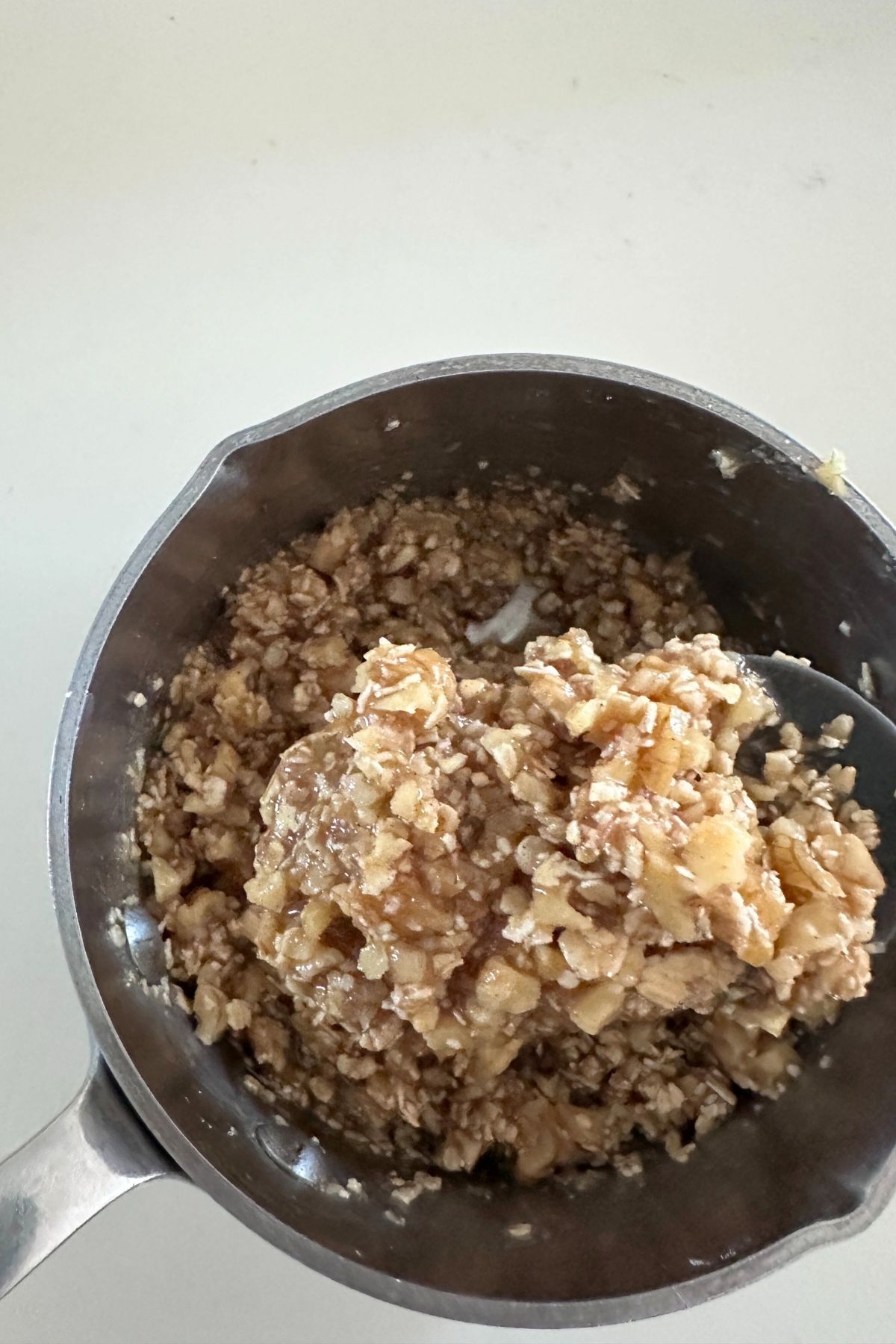 A bowl with walnuts, oats, sugar, flour, cinnamon, and melted butter mixed together.