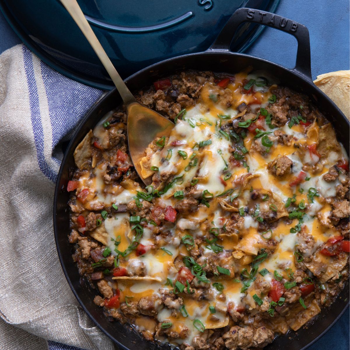 green chile enchiladas in a skillet with cheese and veggies
