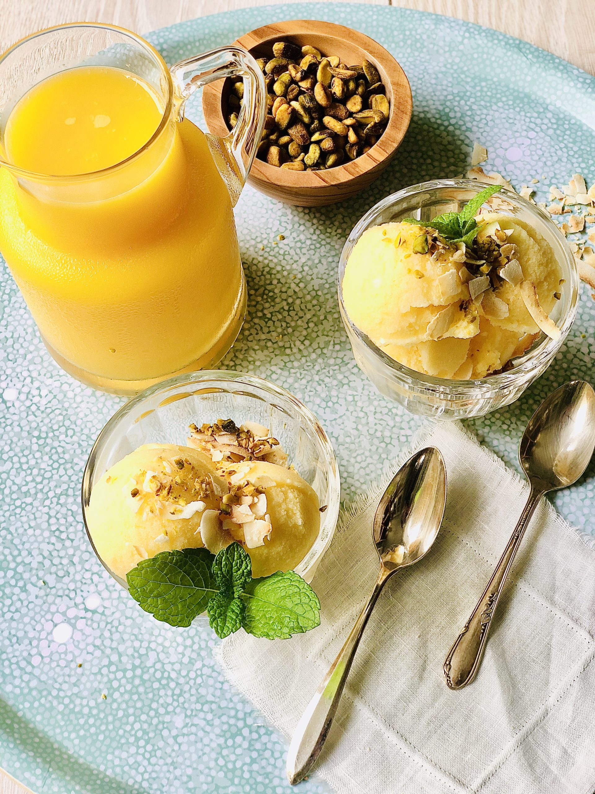 orange juice sherbet in small bowls next to a carafe of orange juice