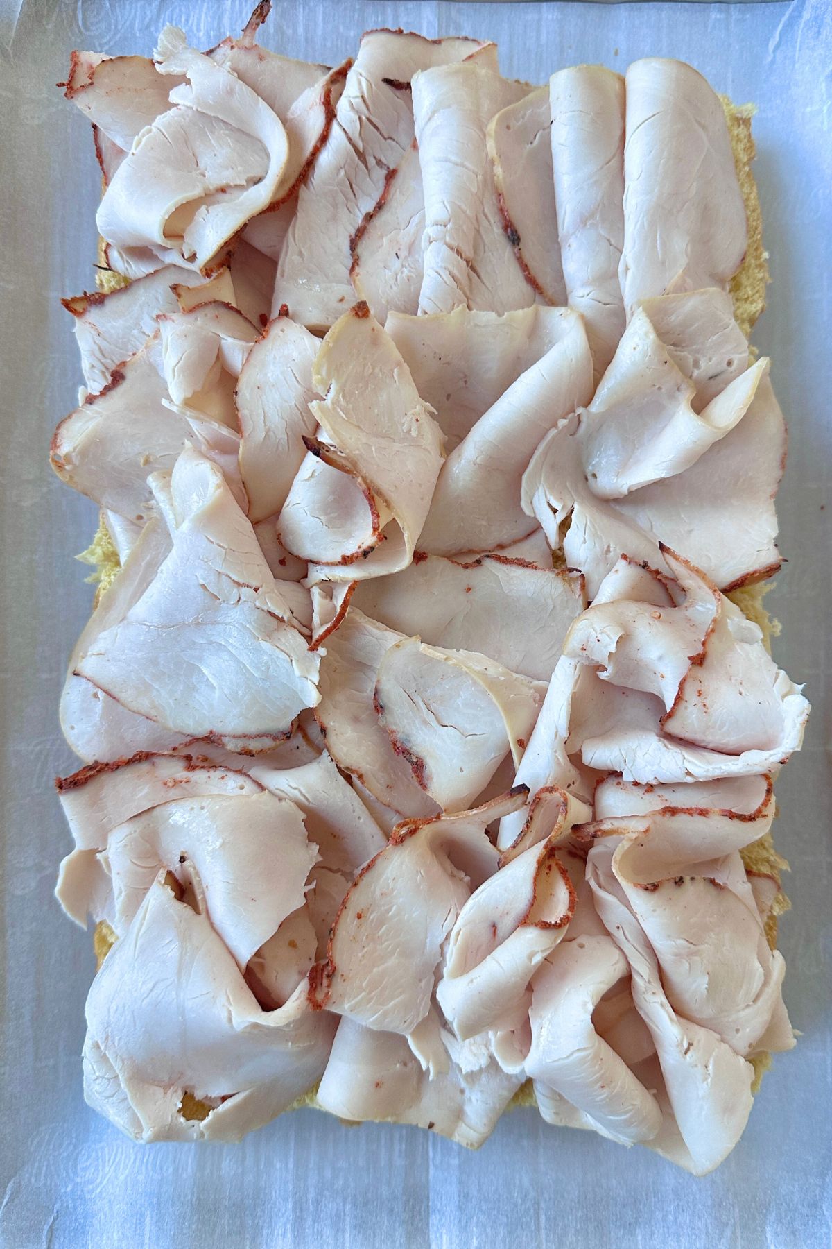 Slices of turkey laid on top of the sliced sliders.