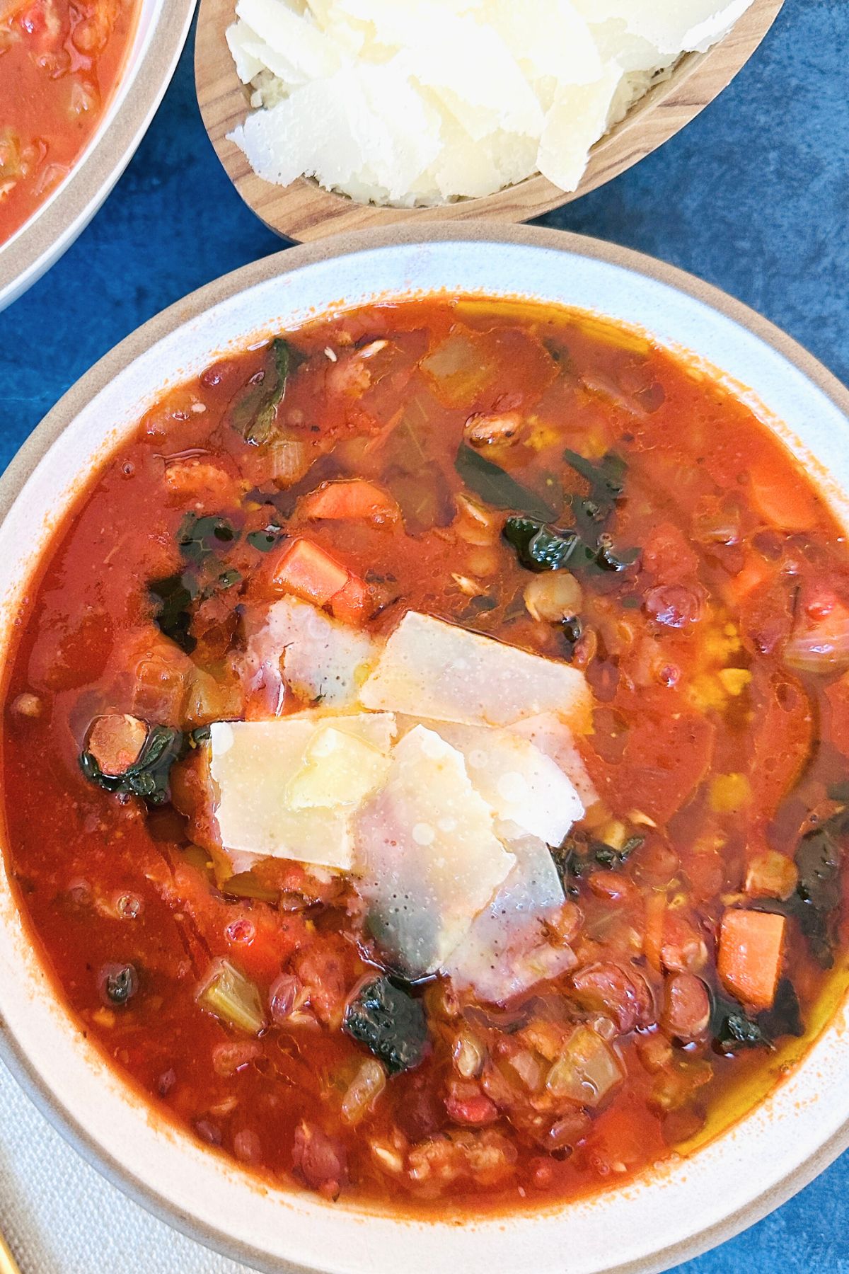 Close-up of a bowl of sausage lentil soup topped with fresh parmesan cheese.