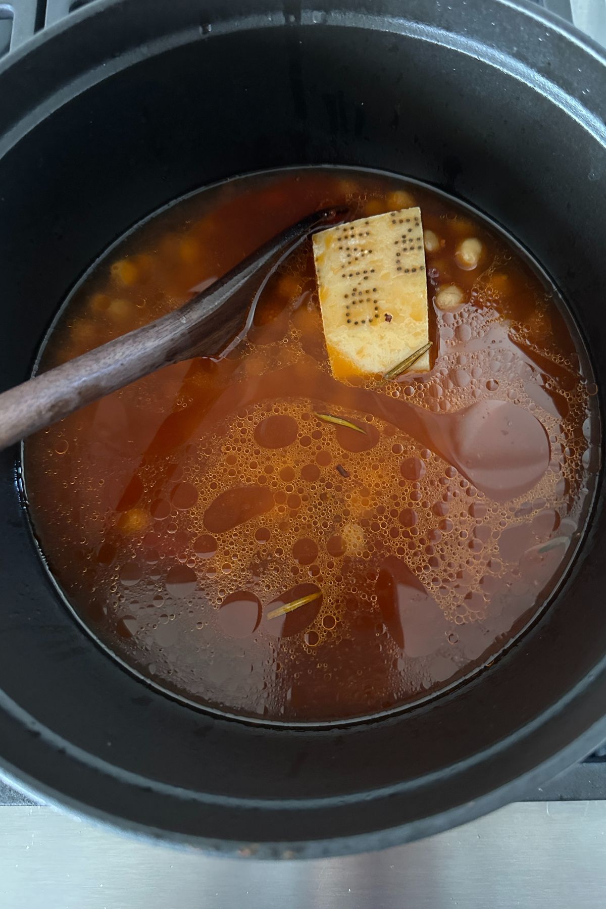 Tomto paste, salt, chickpeas, broth, and Parmesan rind in the pot, ready to simmer and create a creamy base.