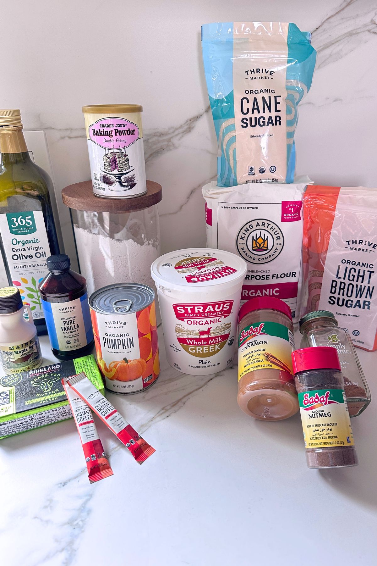 Ingredients for pumpkin coffee cake arranged on a counter including pumpkin purée, flours, sugars, spices, butter, milk, and eggs-free mix.
