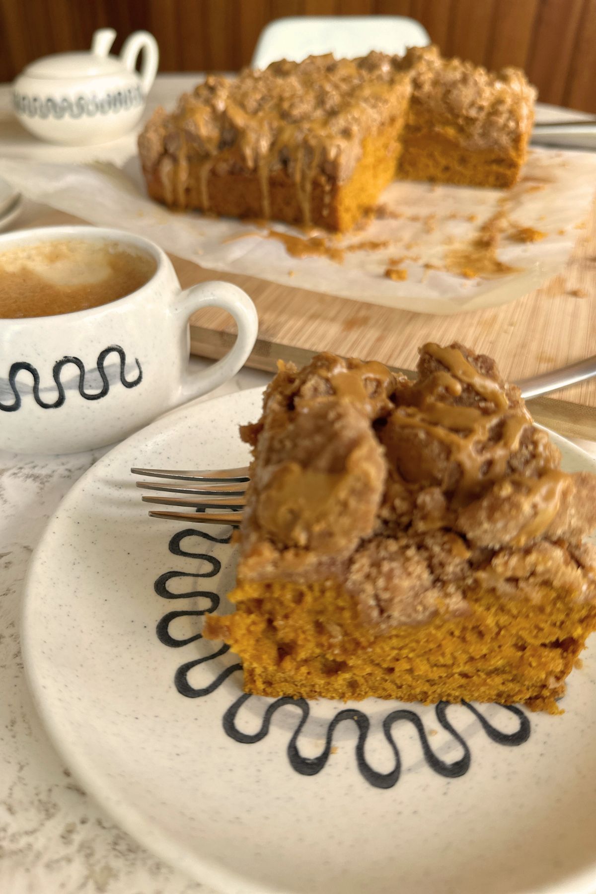 A square of pumpkin coffee cake on a plate, cut and ready to eat, crisp crumb topping visible.