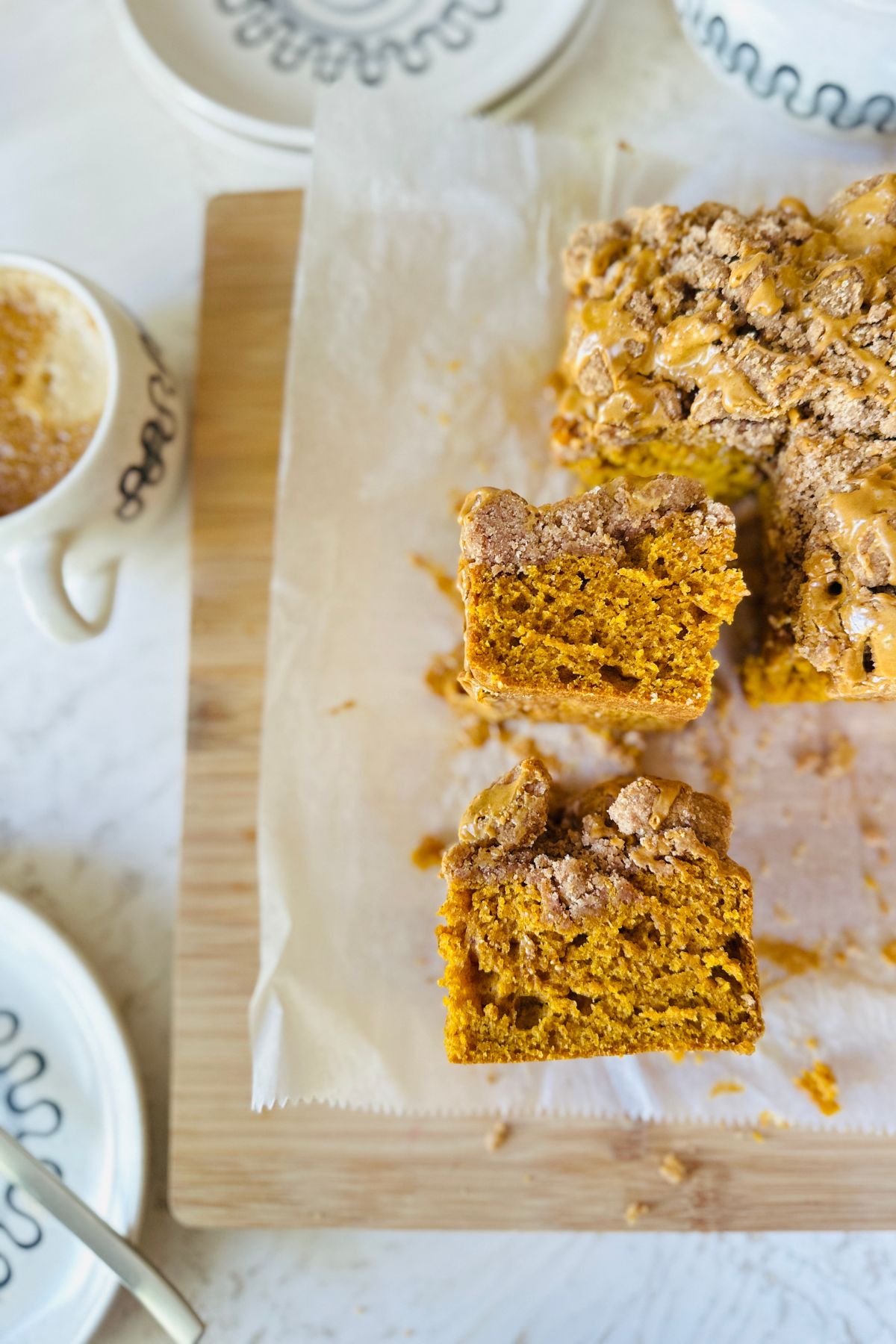 Pumpkin coffee cake sliced, lying on parchment paper, showing tender crumb and cinnamon streusel topping.