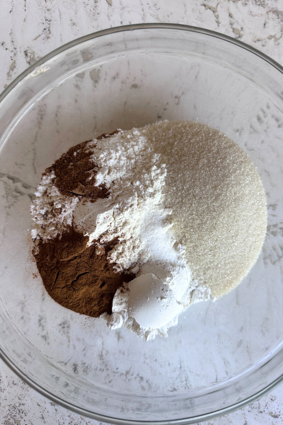 Flour, sugars, cinnamon, nutmeg, and salt in a glass mixing bowl.