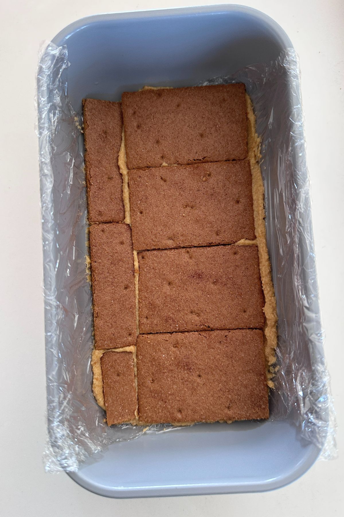 Pumpkin cream in the bottom of plastic lined loaf pan topped with a single layer of graham crackers.
