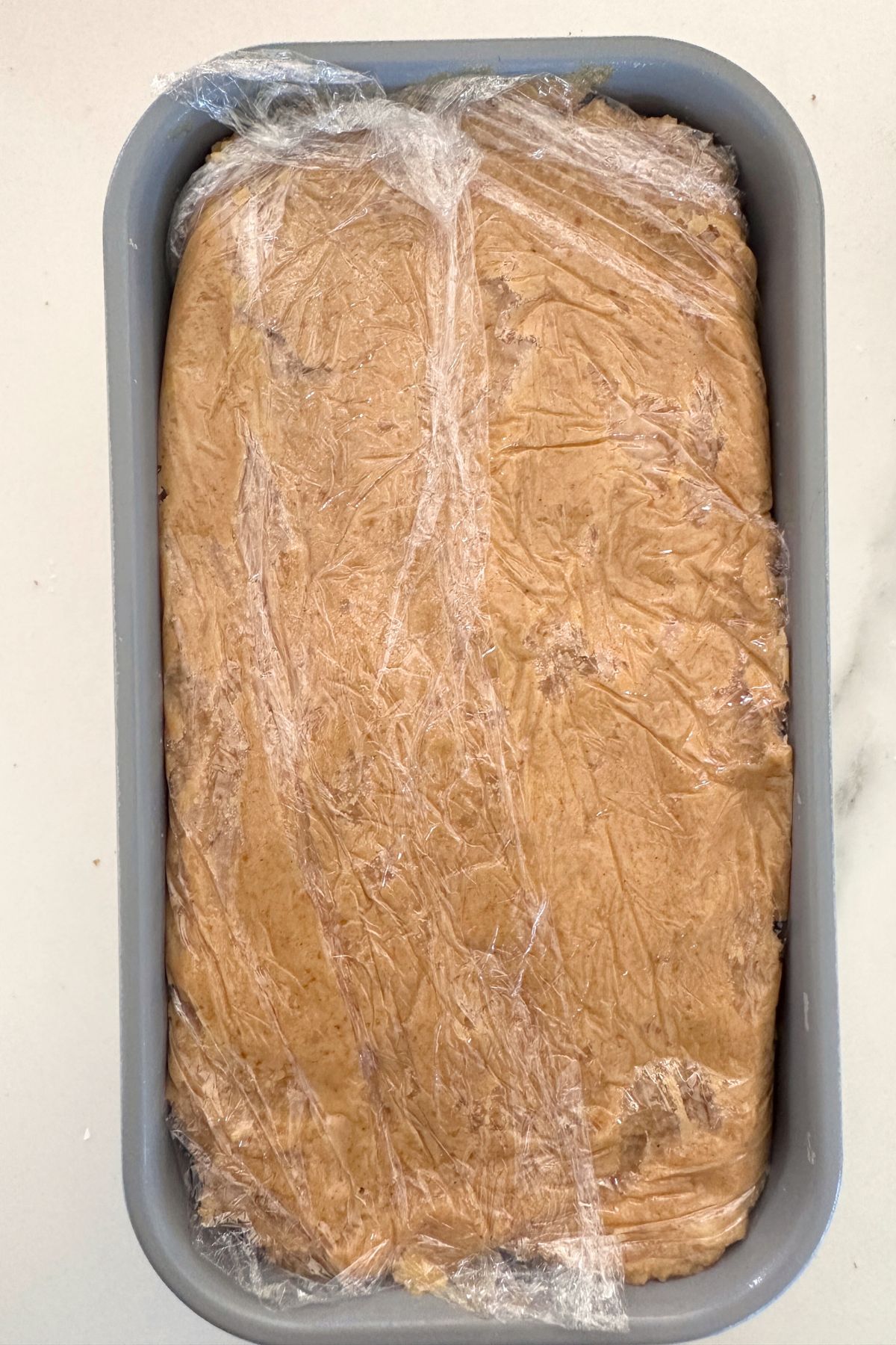 Pumpkin icebox cake assembled and covered with plastic wrap, ready to chill overnight.