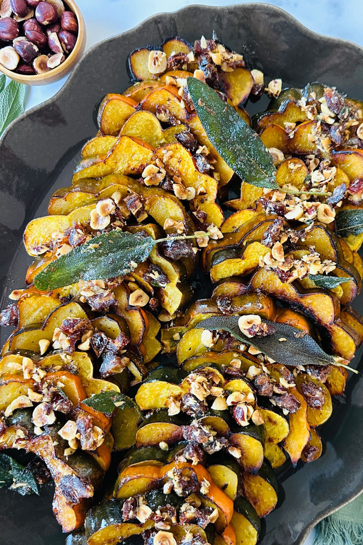 Close-up of roasted acorn squash arranged on a platter covered with warm butter mixture, ready to eat.