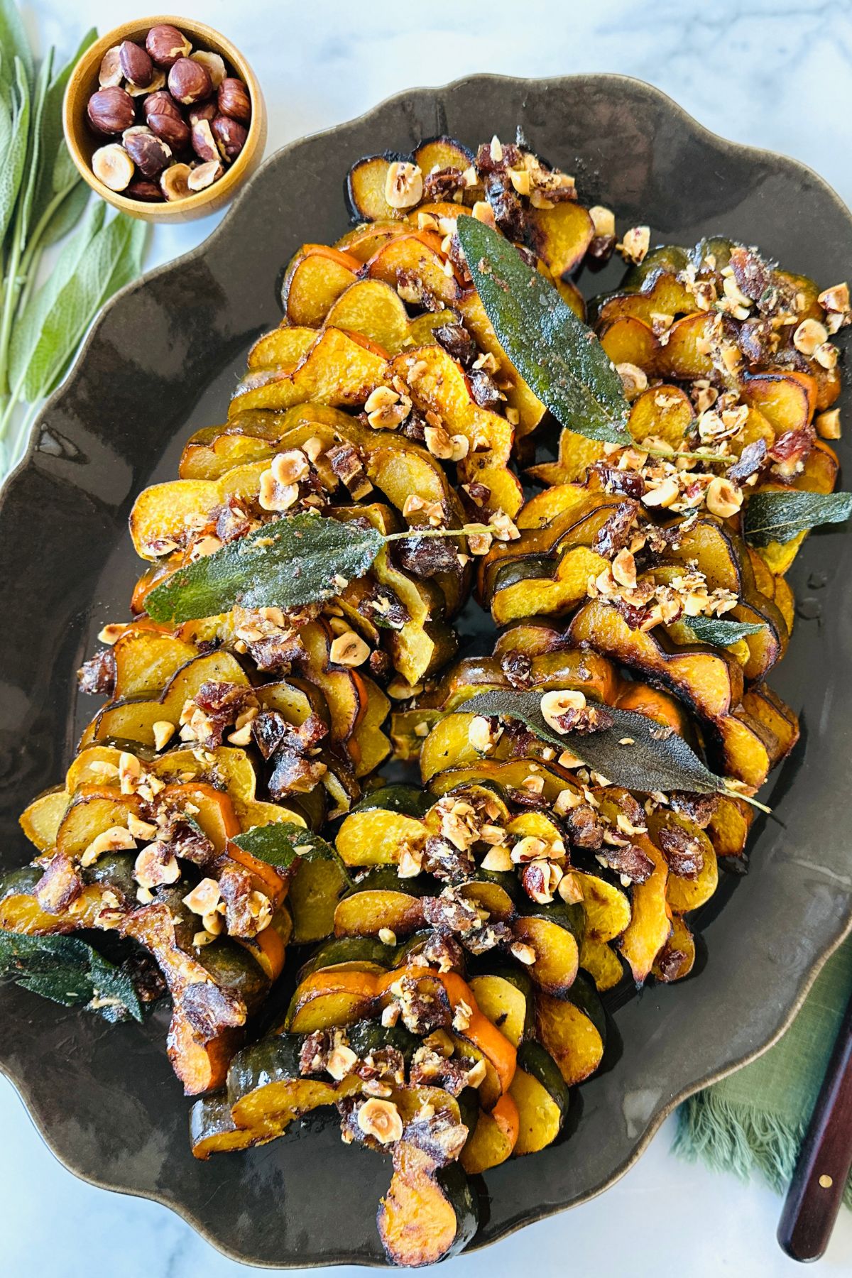 Roasted acorn squash arranged on a platter covered with warm butter mixture, ready to eat.