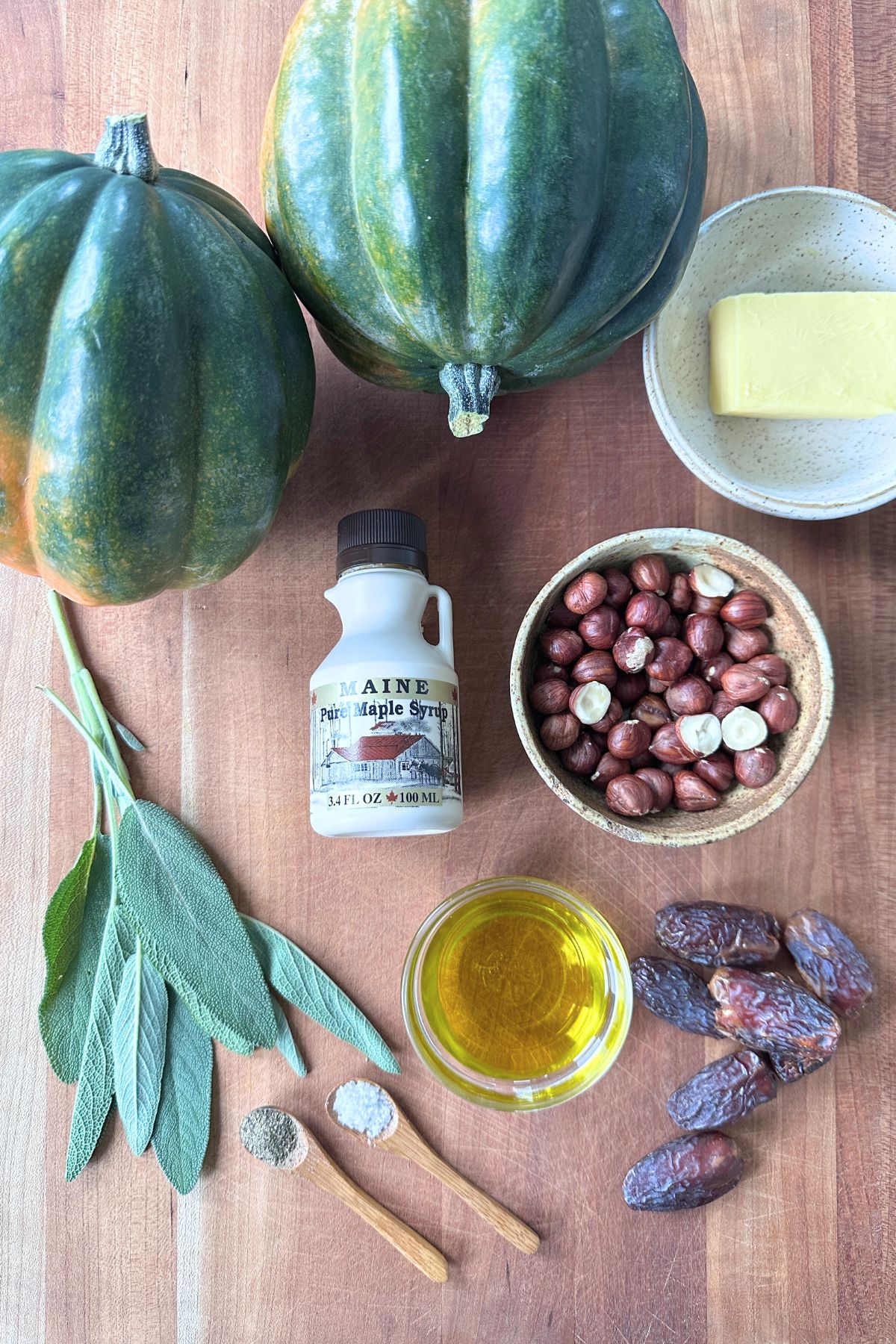 Ingredients for roasted acorn squash laid out on a wooden cutting board.