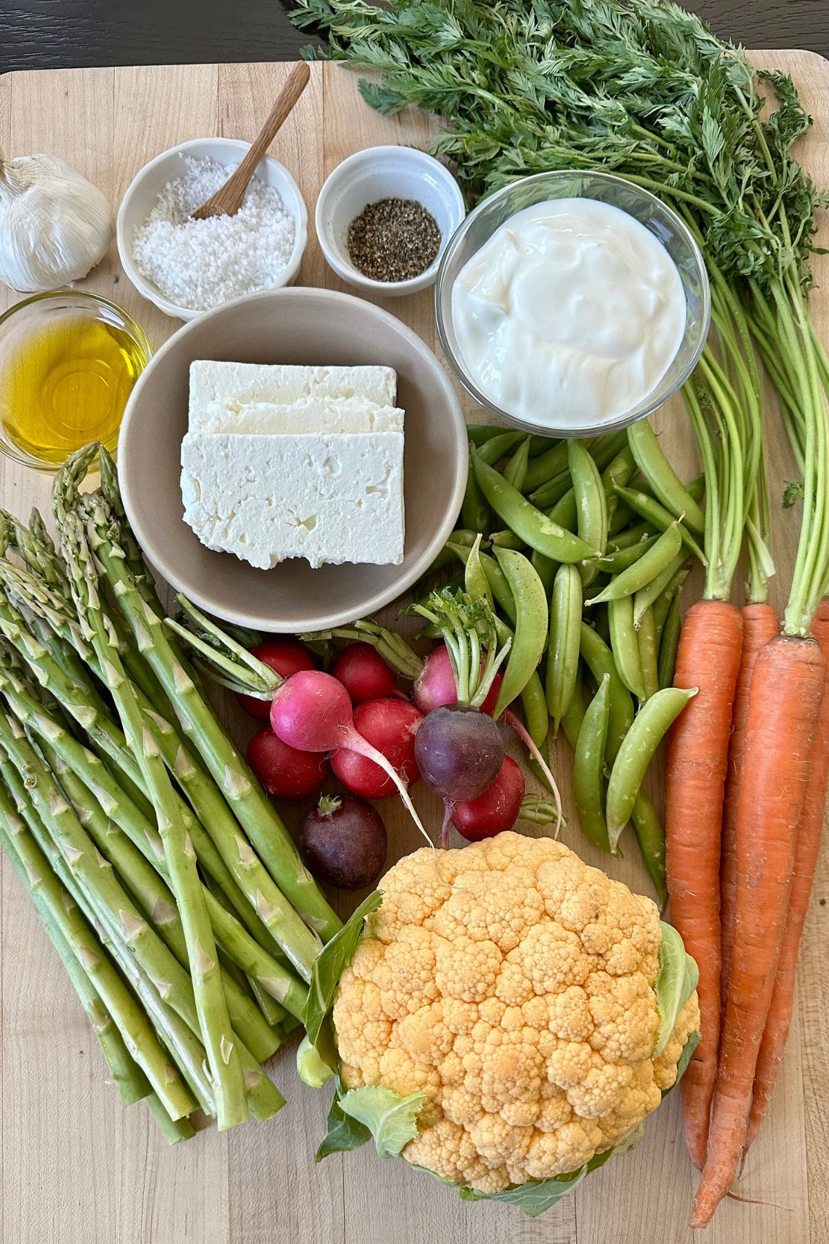 raw veggies and a block of feta sit on top of a counter