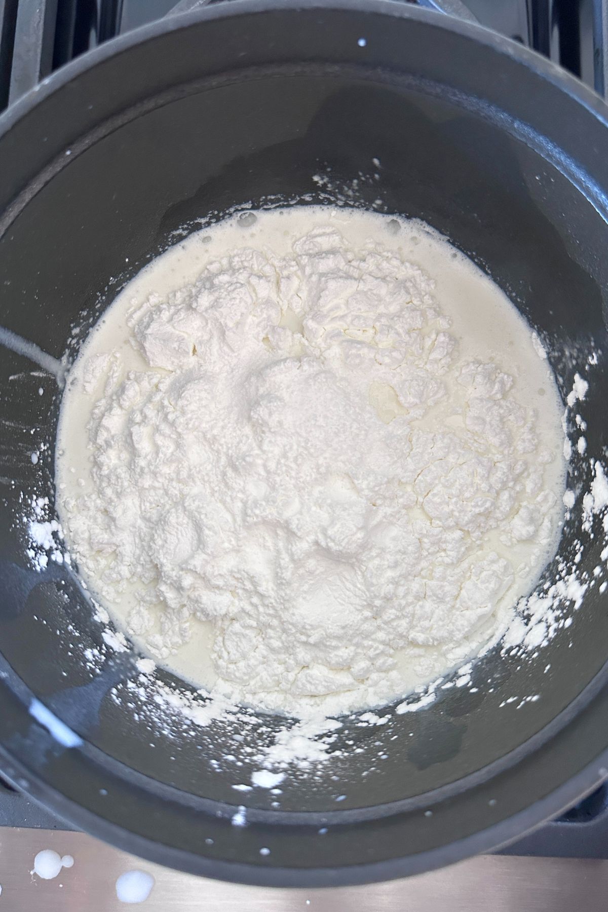 A saucepan filled with milk, cream, egg yolks, cornstarch, and salt, ready to cook over medium-high heat.