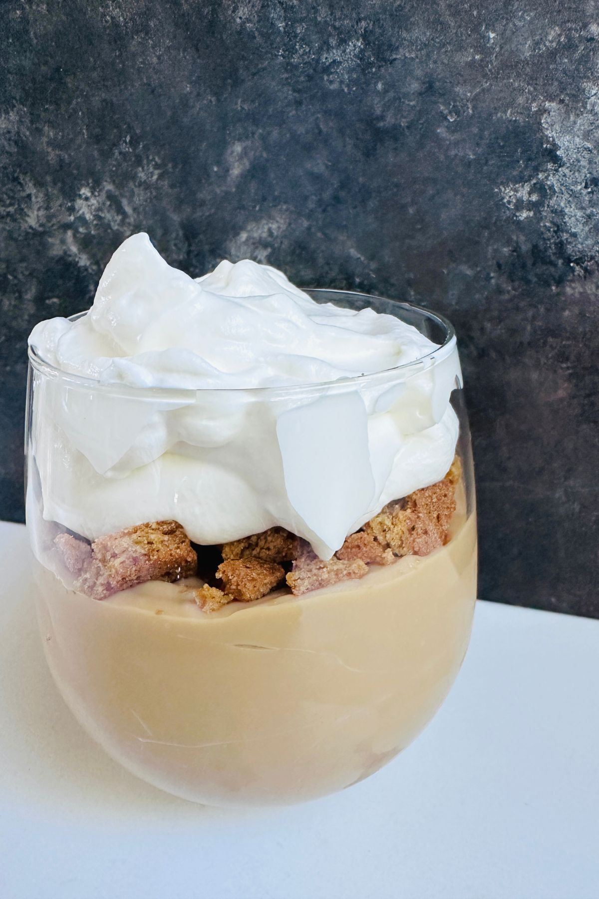 Assembled pudding parfaits set against a dark backdrop, showing distinct layers and a smooth, creamy texture.