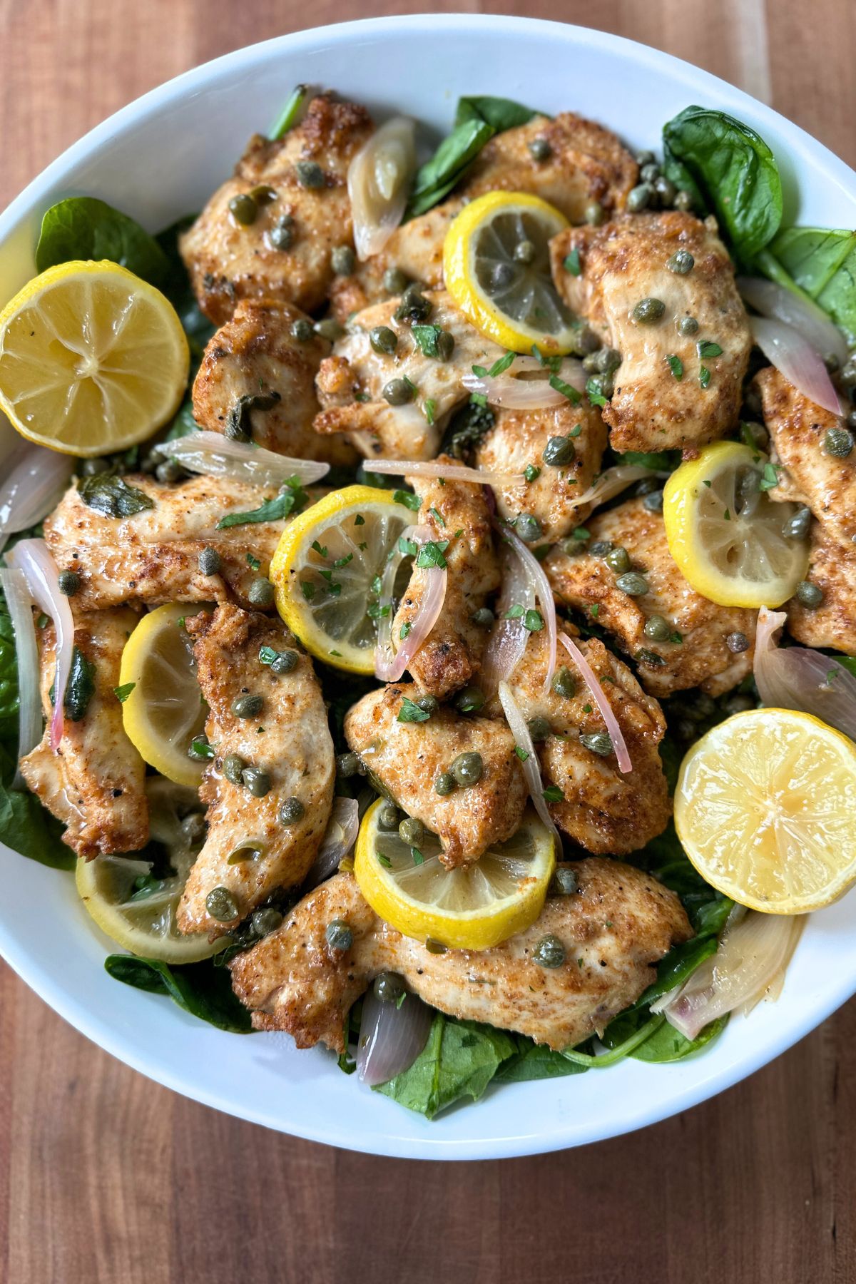 Roasted chicken piccata in a white bowl, ready to serve.