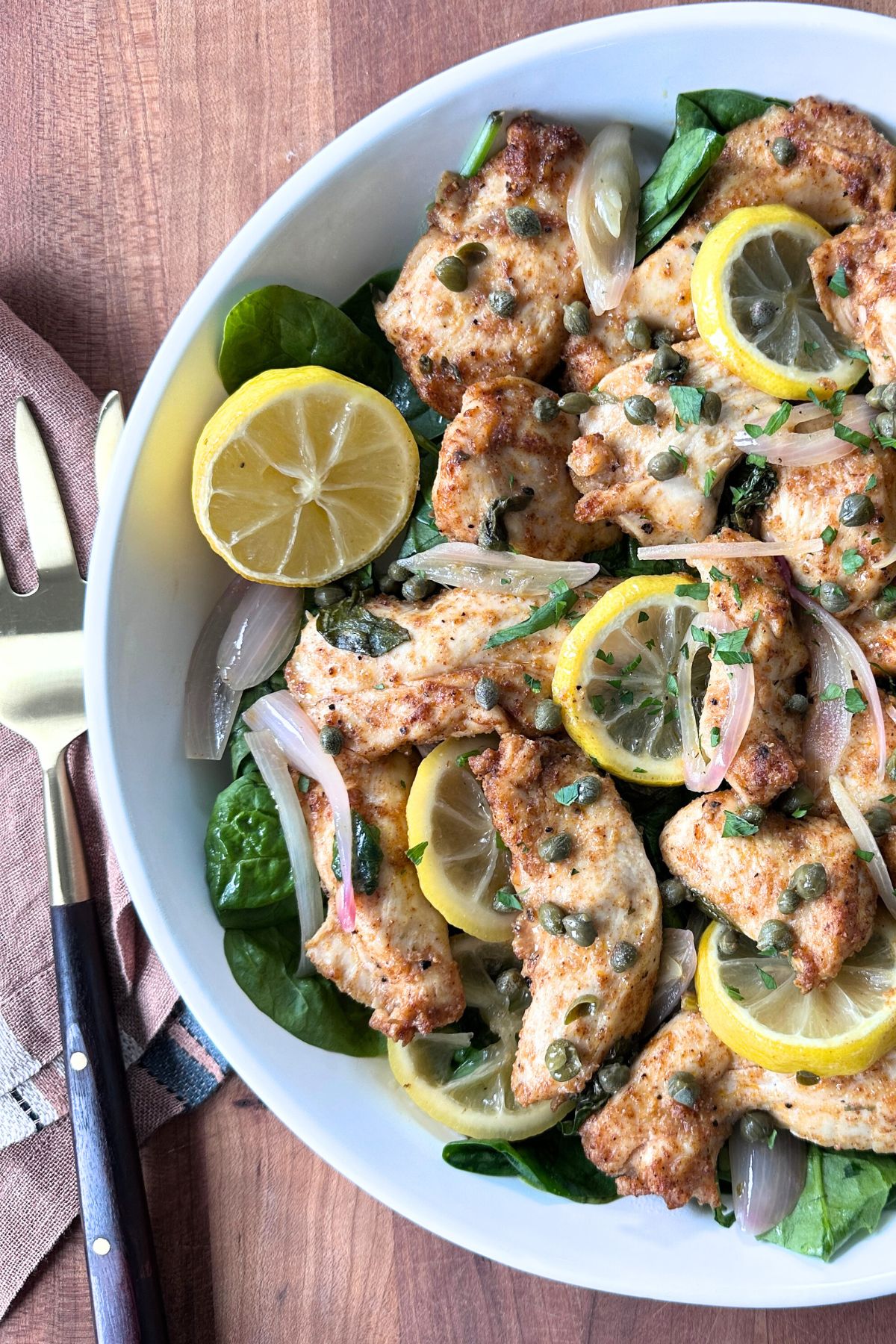 Sheet pan chicken piccata topped with capers and fresh lemon slices.