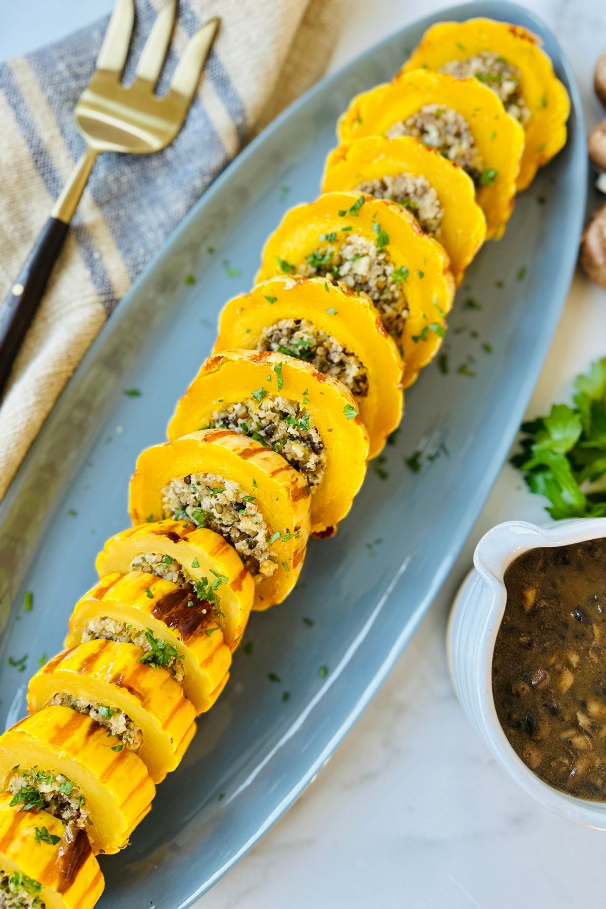Sliced stuffed delicata squash arranged in a line on a blue serving tray. 