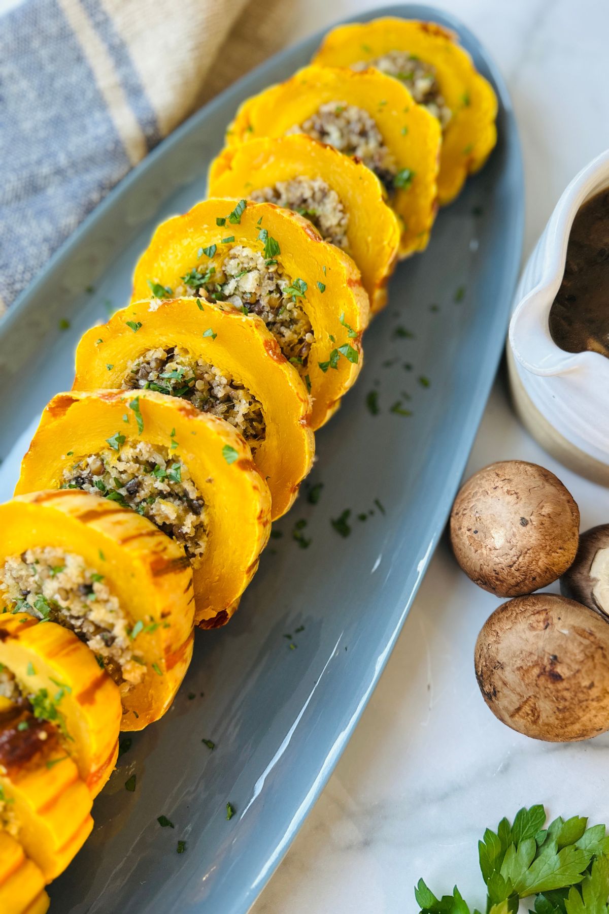 Close-up of sliced stuffed delicata squash arranged in a line on a blue serving tray. 