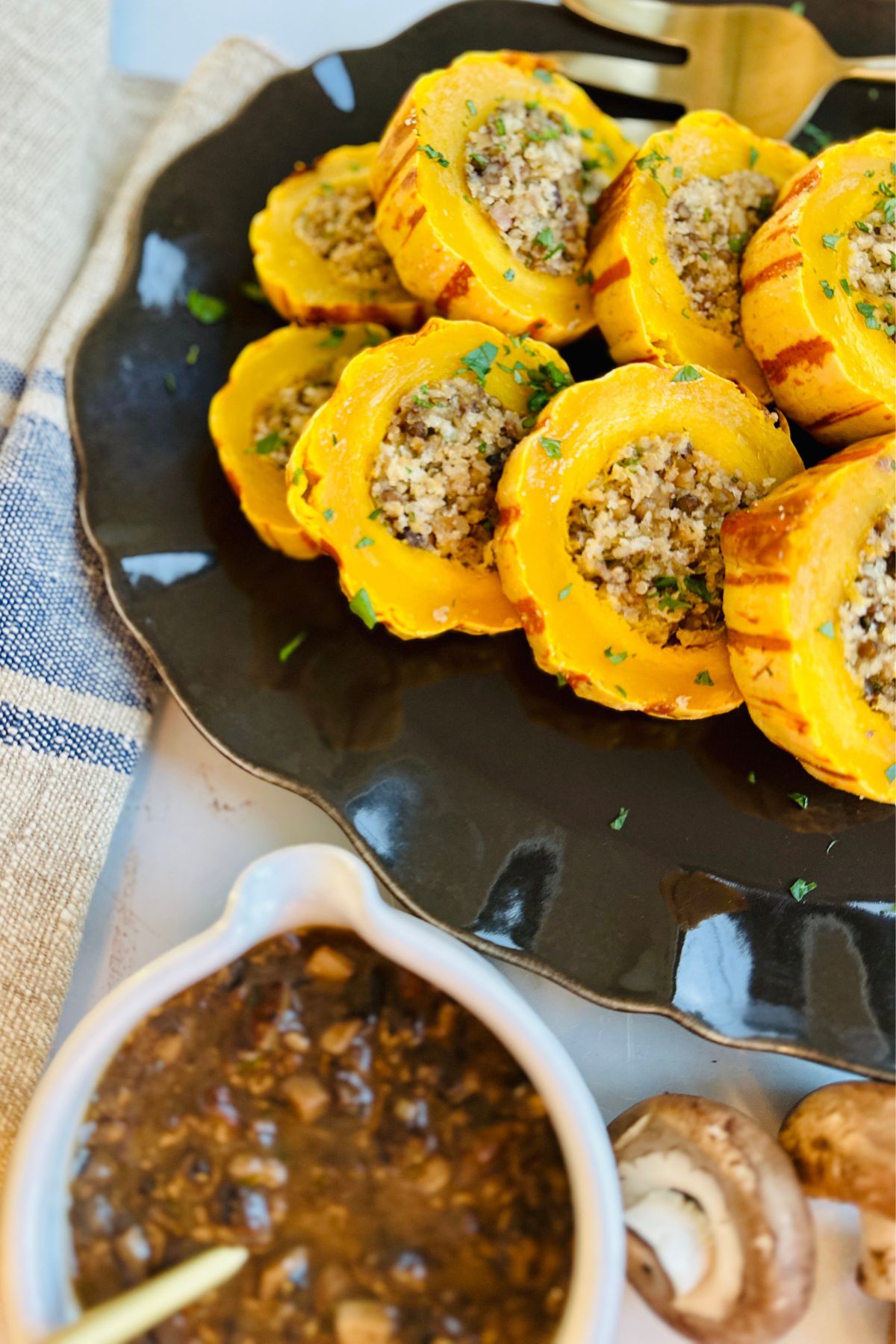 Close-up of sliced delicata squash arranged on a black serving tray. 