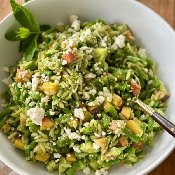 a finished summer orzo salad with chewy orzo pasta, fresh peaches, feta cheese, and blanched veggies mixed with a basil mint vinaigrette for a fresh spin on a summer classic
