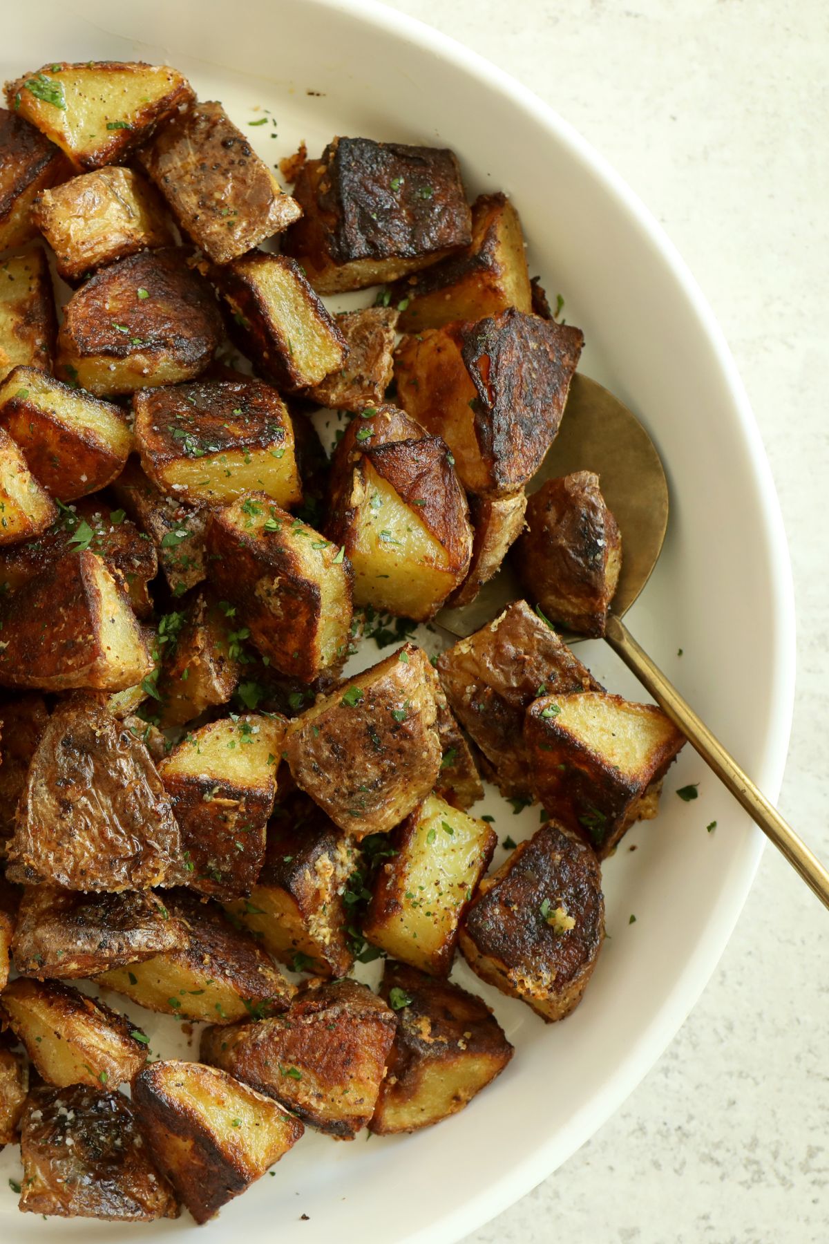 a white serving bowl filled with roasted truffle potatoes