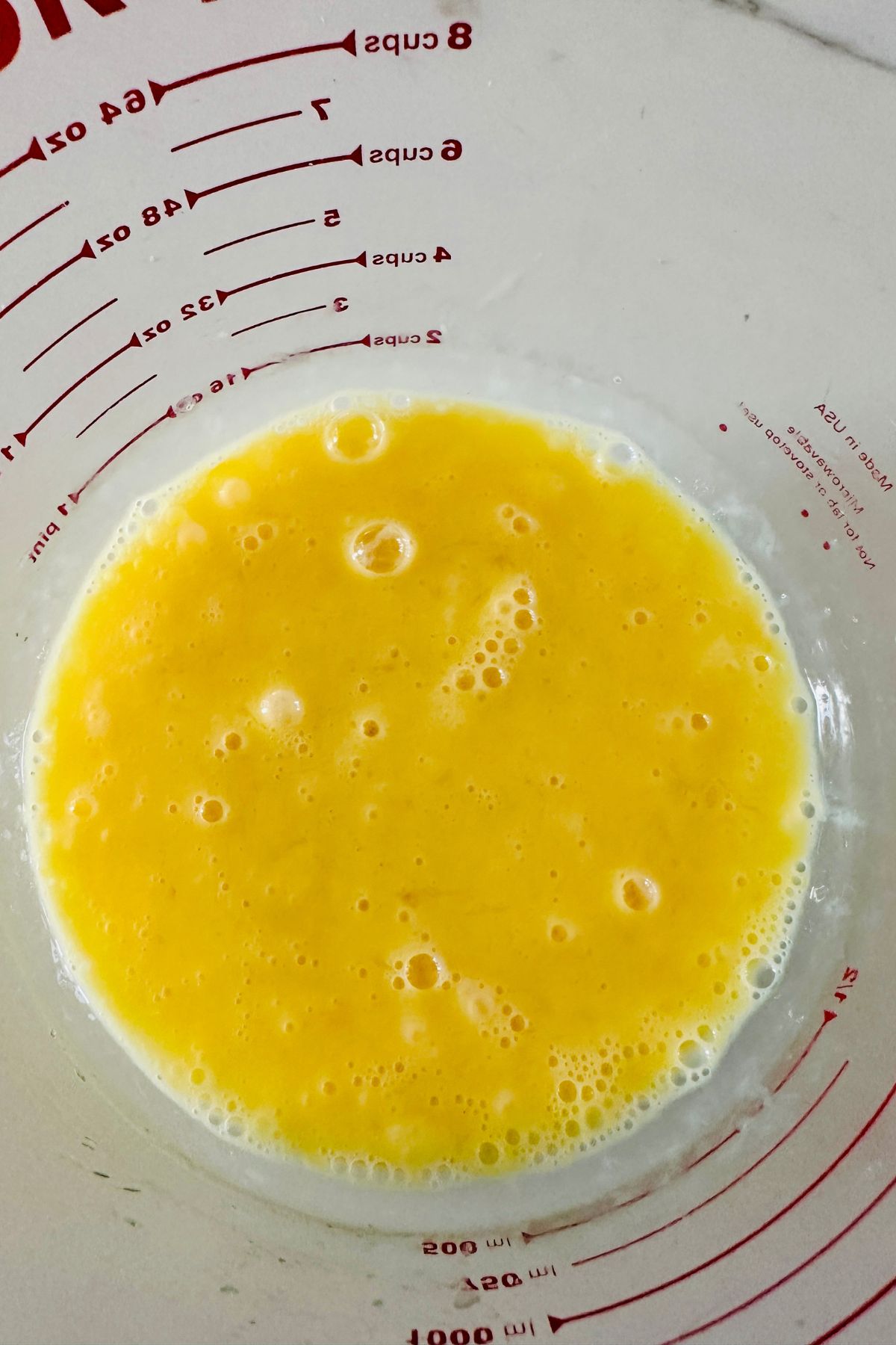 Whisked eggs and lemon juice in a glass measuring cup.